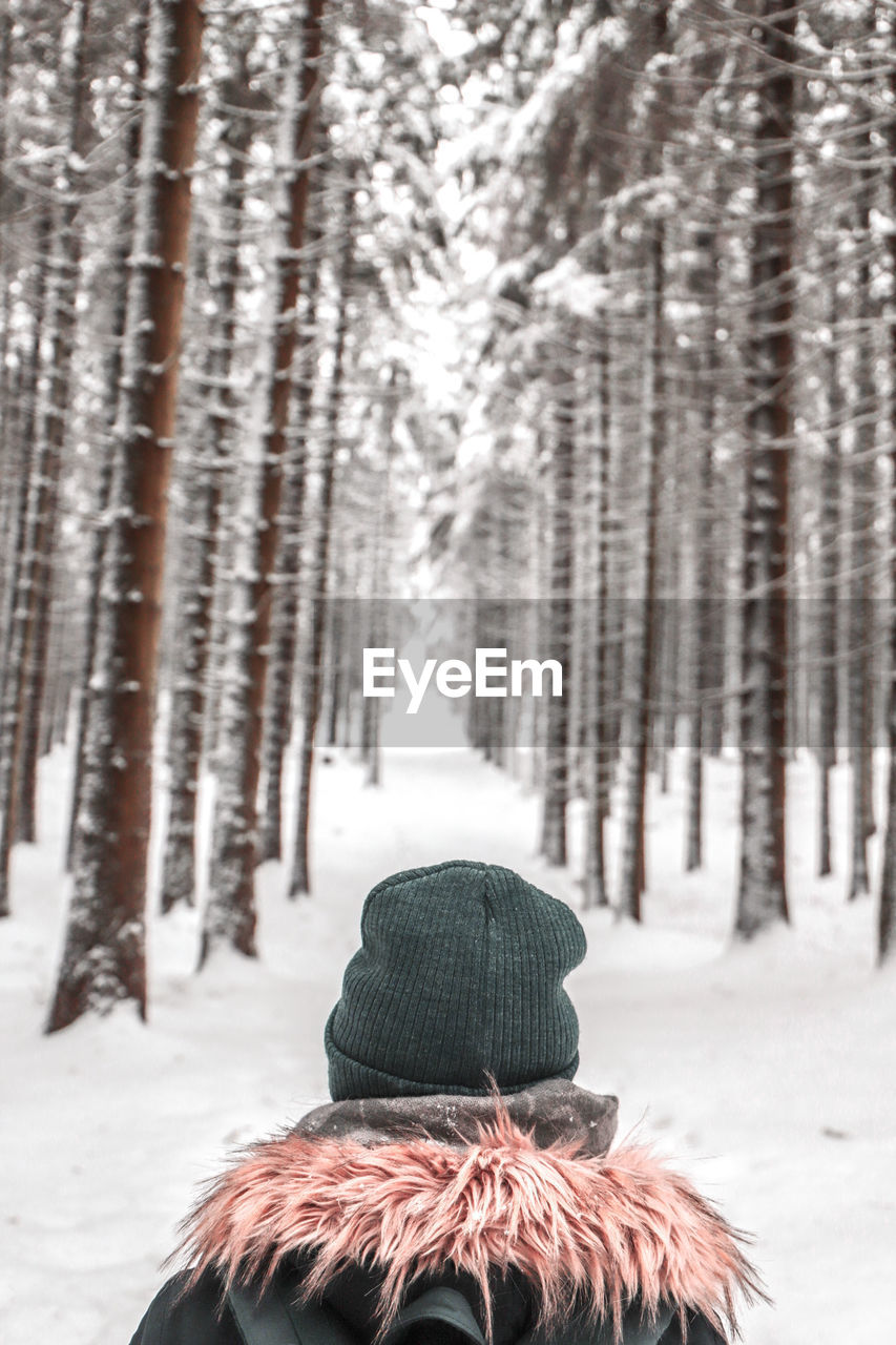 REAR VIEW OF MAN IN SNOW COVERED FOREST