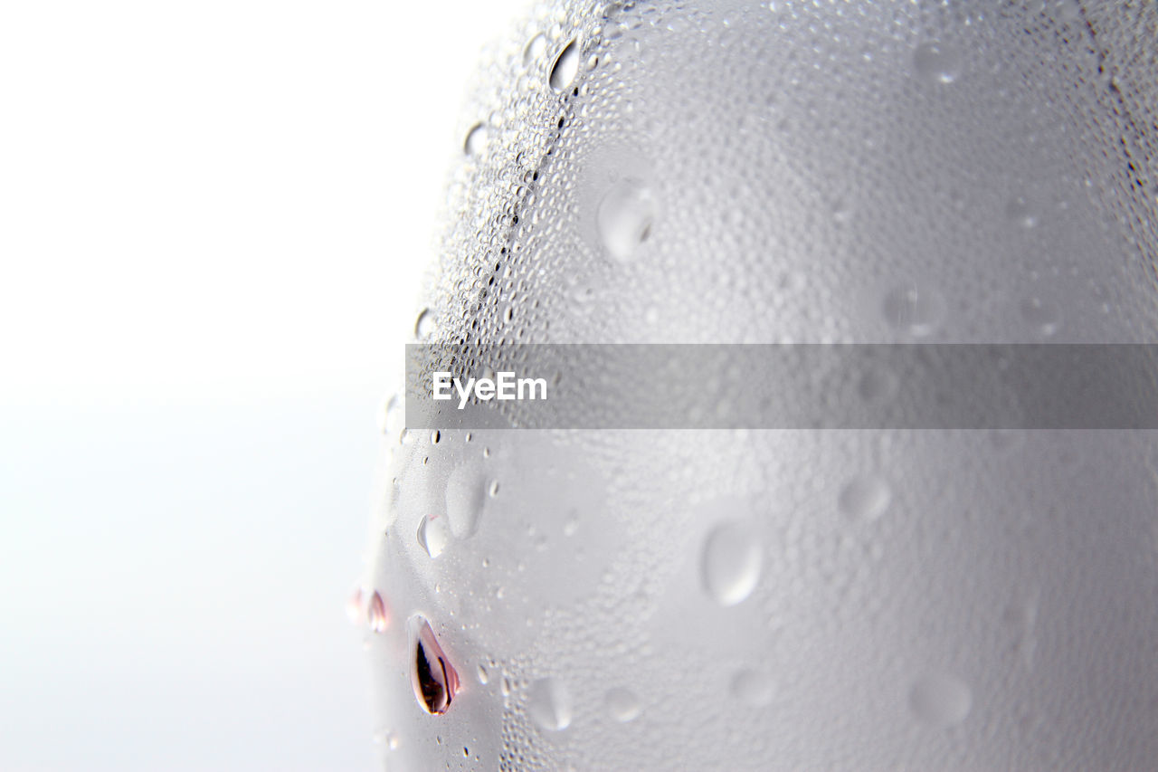 Close-up of wet glass against white background