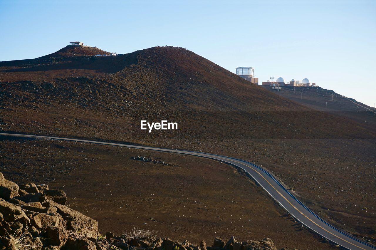 Scenic view of road by volcanic mountains against clear sky