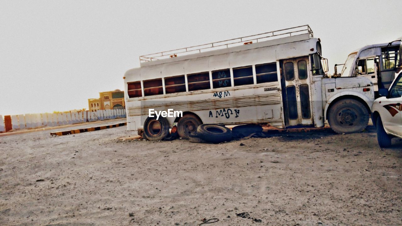 ABANDONED TRUCK ON SAND AGAINST CLEAR SKY