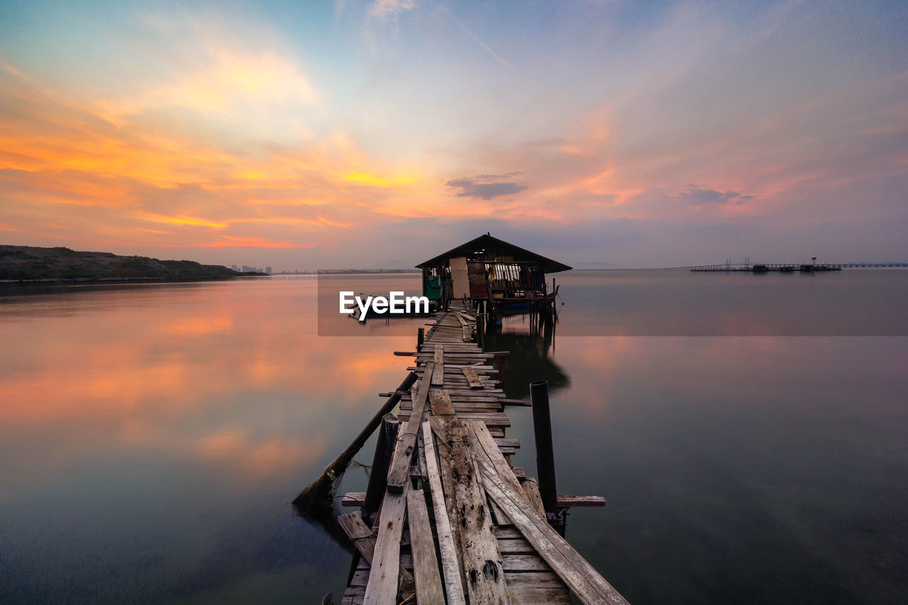 Pier over lake against sky during sunset