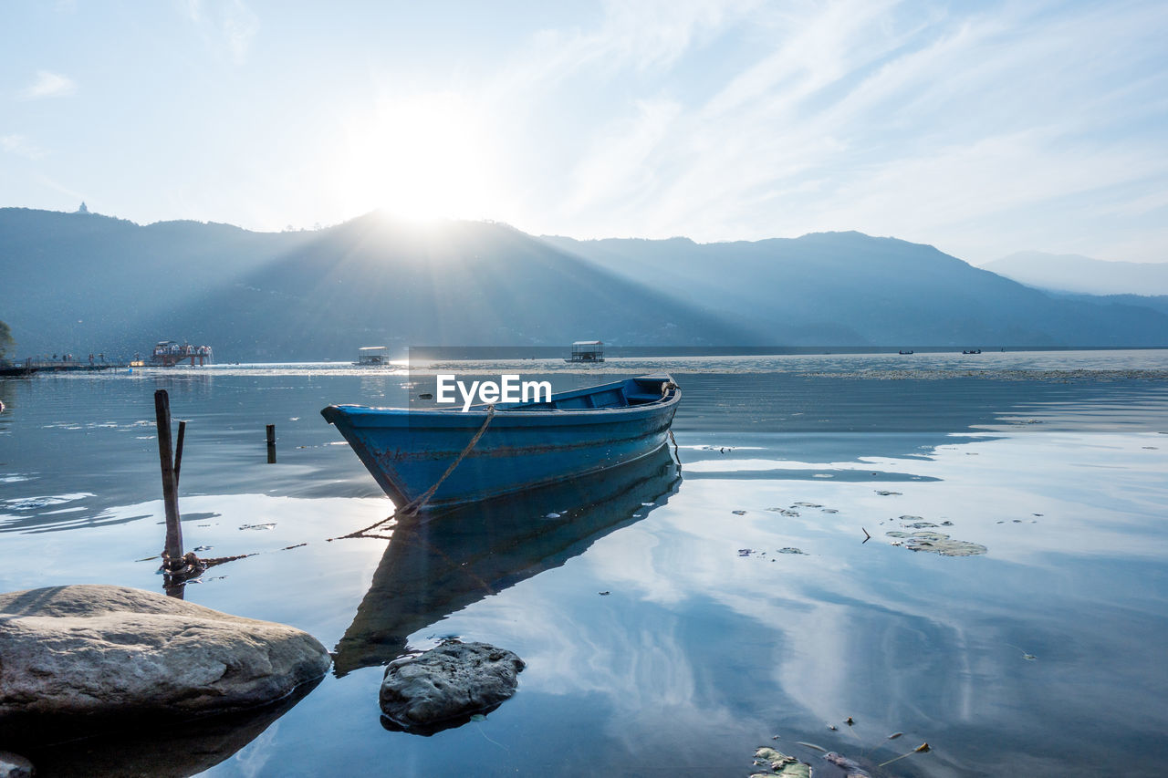 Boats moored on lake against sky