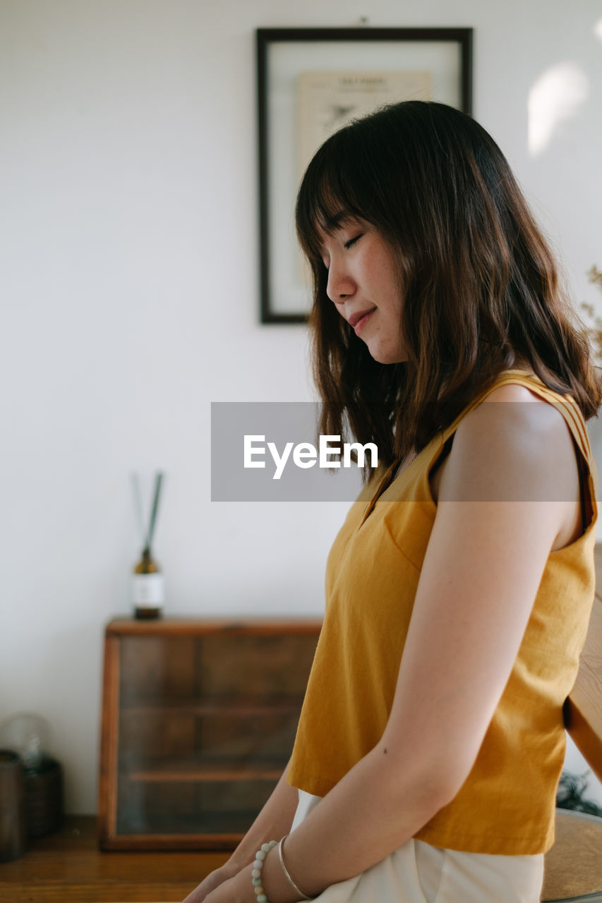 Woman looking away while standing at home