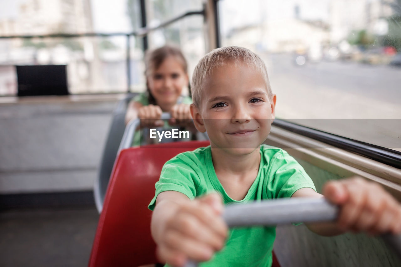 Kids ride in empty tram and look at the window with smile, public transportation, city tramway