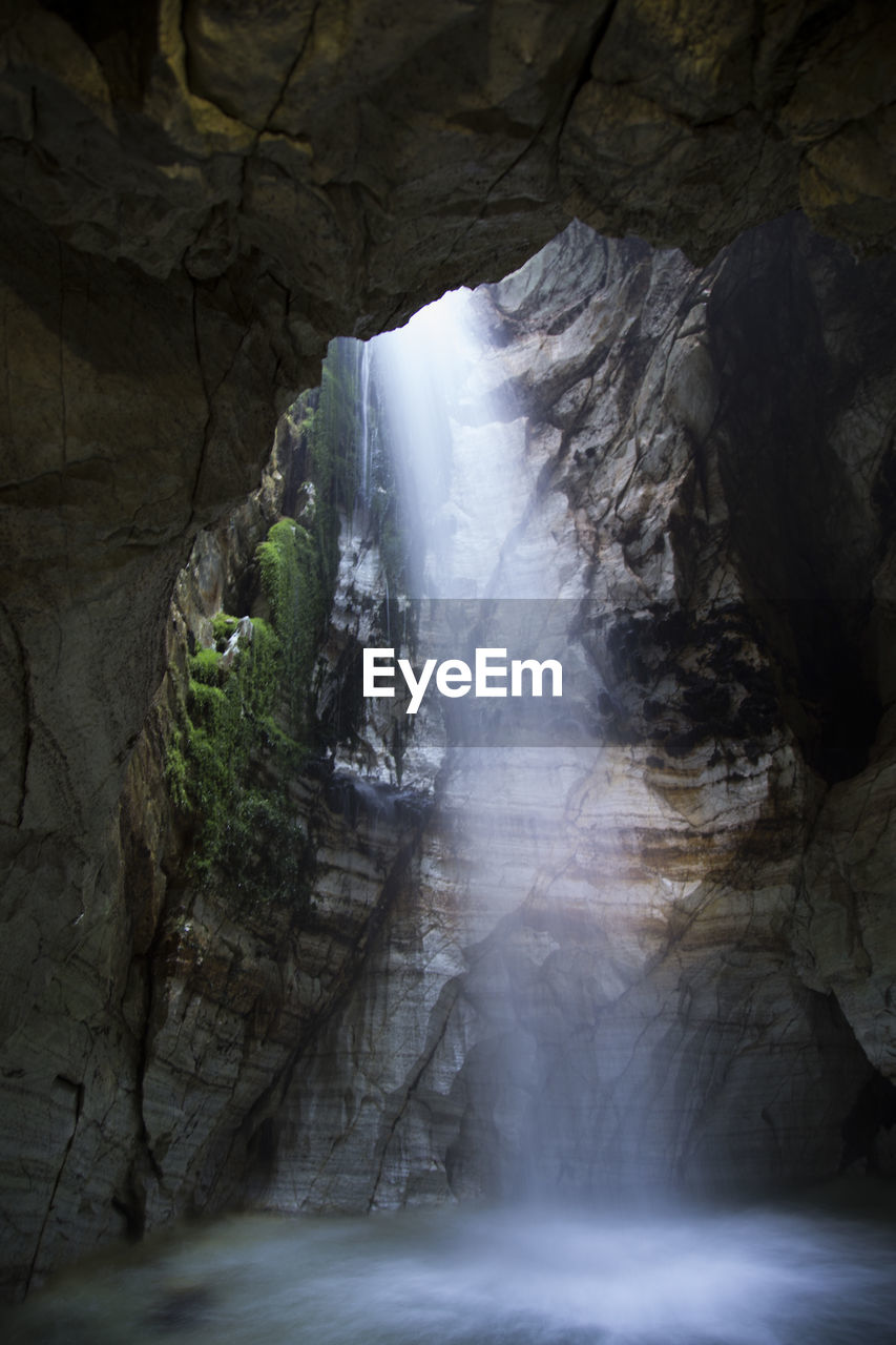 Light shining through waterfall in a an ancient cave