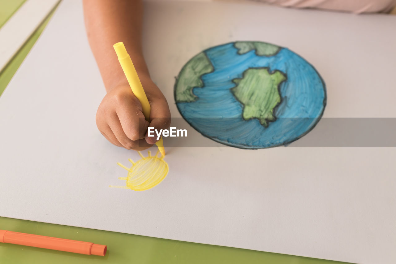 Girl drawing sun on cardboard paper at home