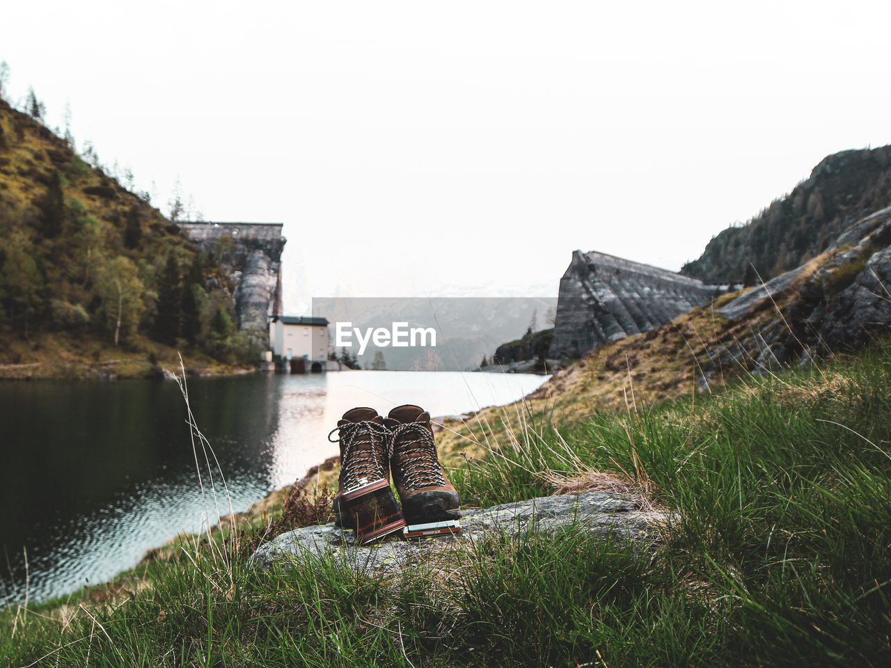 Scenic view of boots against an old dam between mountains