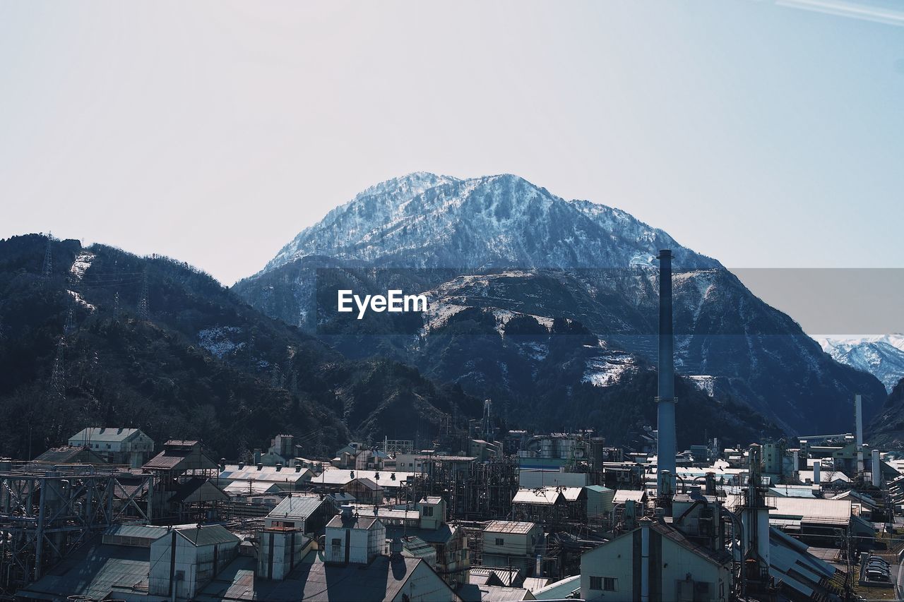 Aerial view of townscape by mountains against clear sky