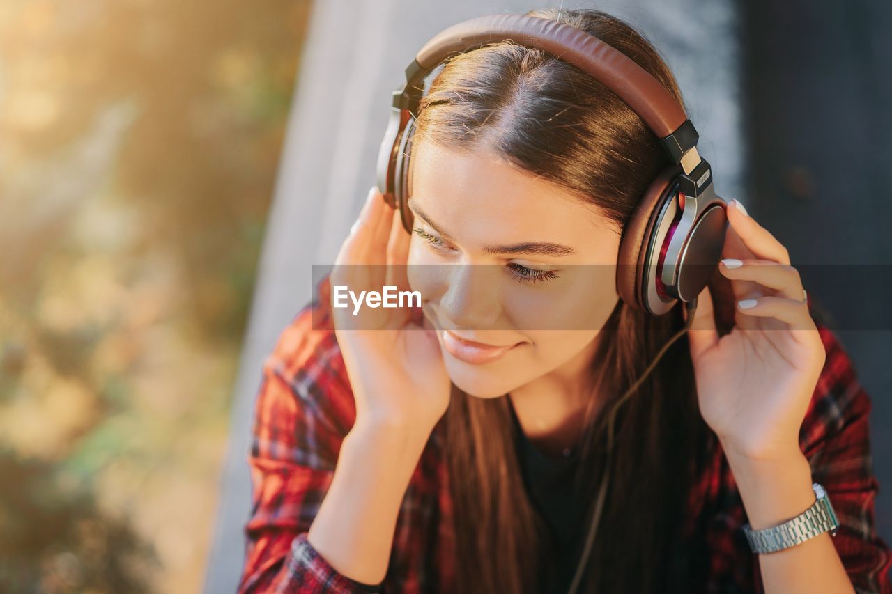 Close-up of young woman listening music on headphones