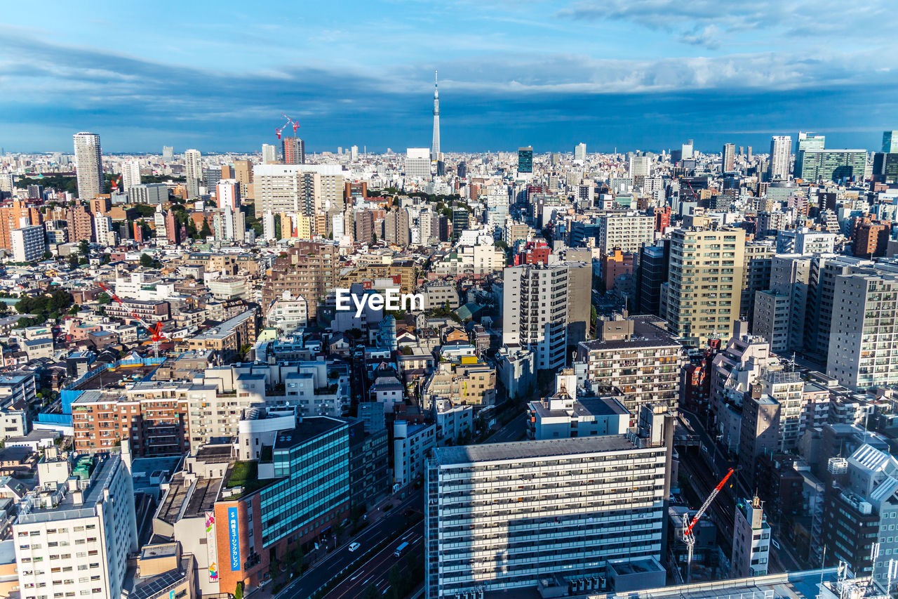 High angle view of city buildings against cloudy sky