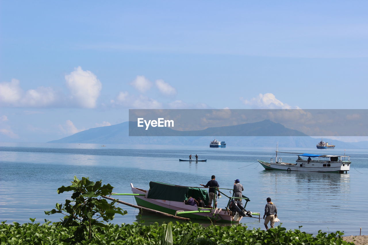 Boats in calm lake against mountain range