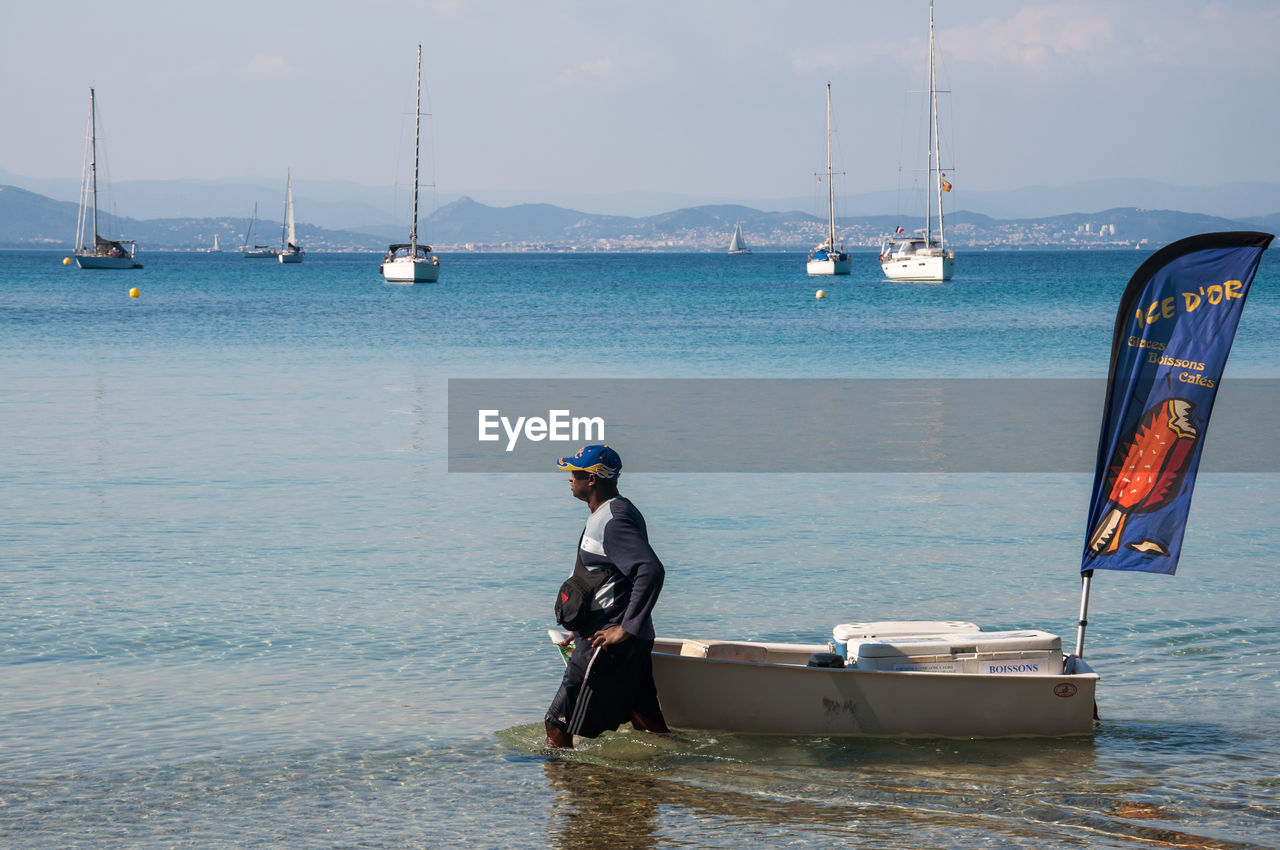 REAR VIEW OF MAN STANDING ON SEA