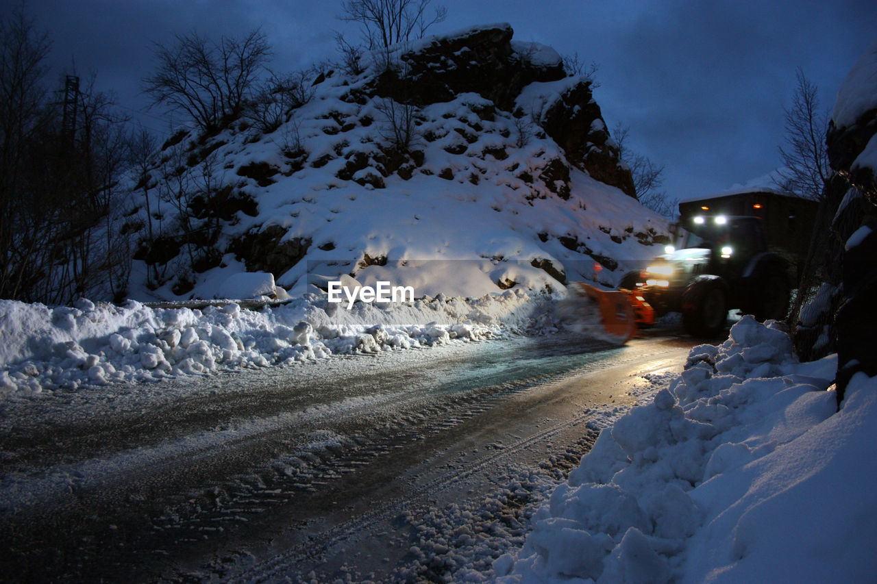 SNOW COVERED ROAD AMIDST FIELD DURING WINTER