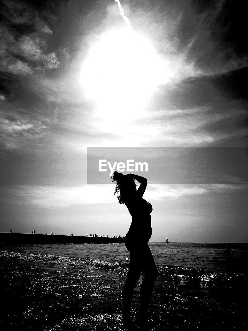 Sensuous woman posing on seashore against sky