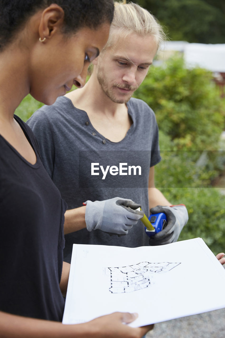 Garden architects looking at blueprint at yard