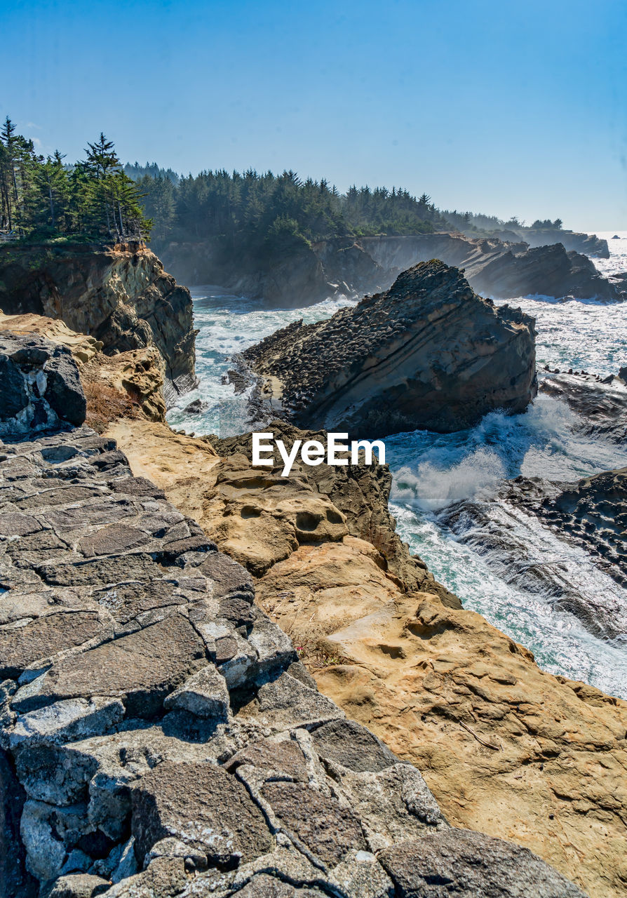 A shoreline with rock formations and crashing waves at shore acres state park in oregon state.