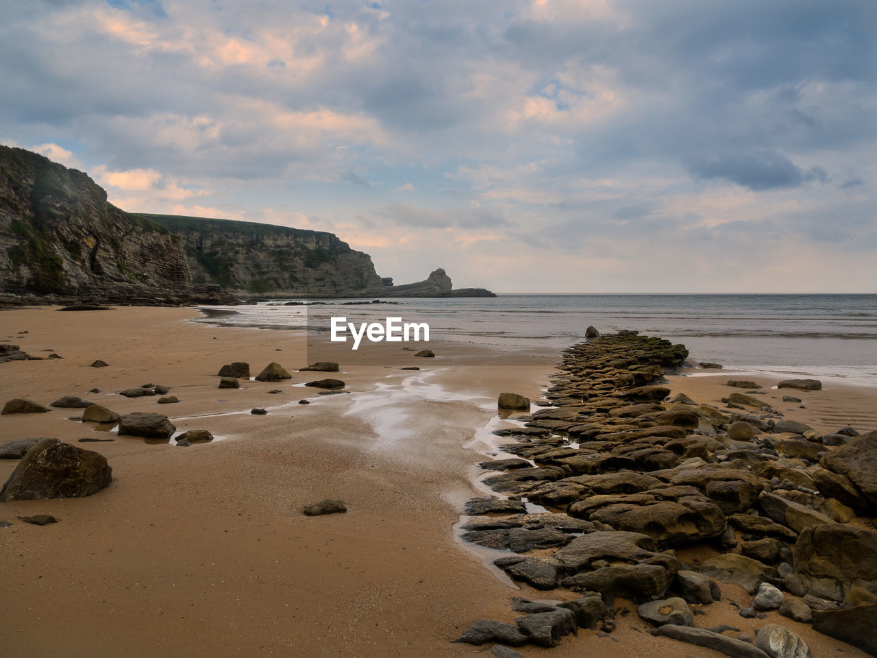 Rocks on beach against sky during sunset