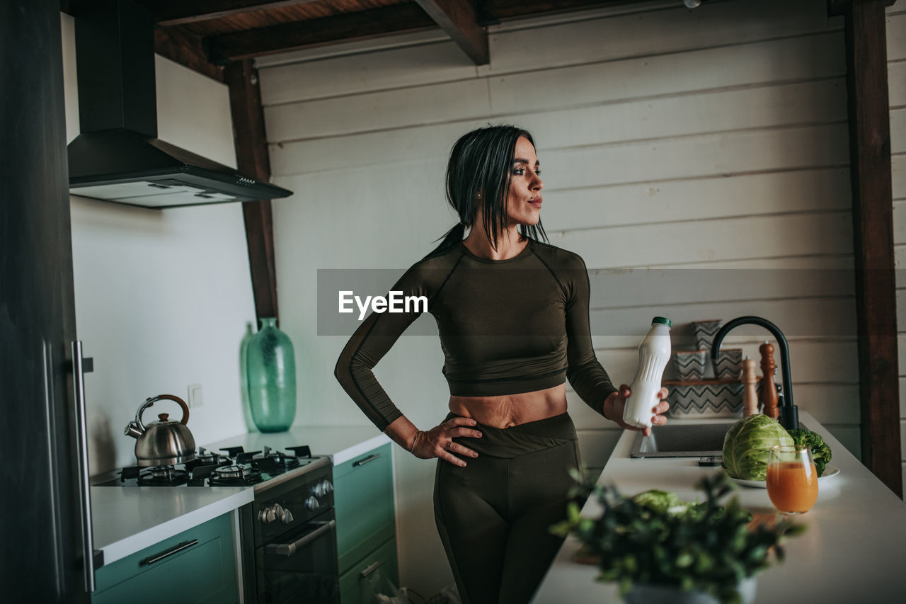 YOUNG WOMAN STANDING AT HOME