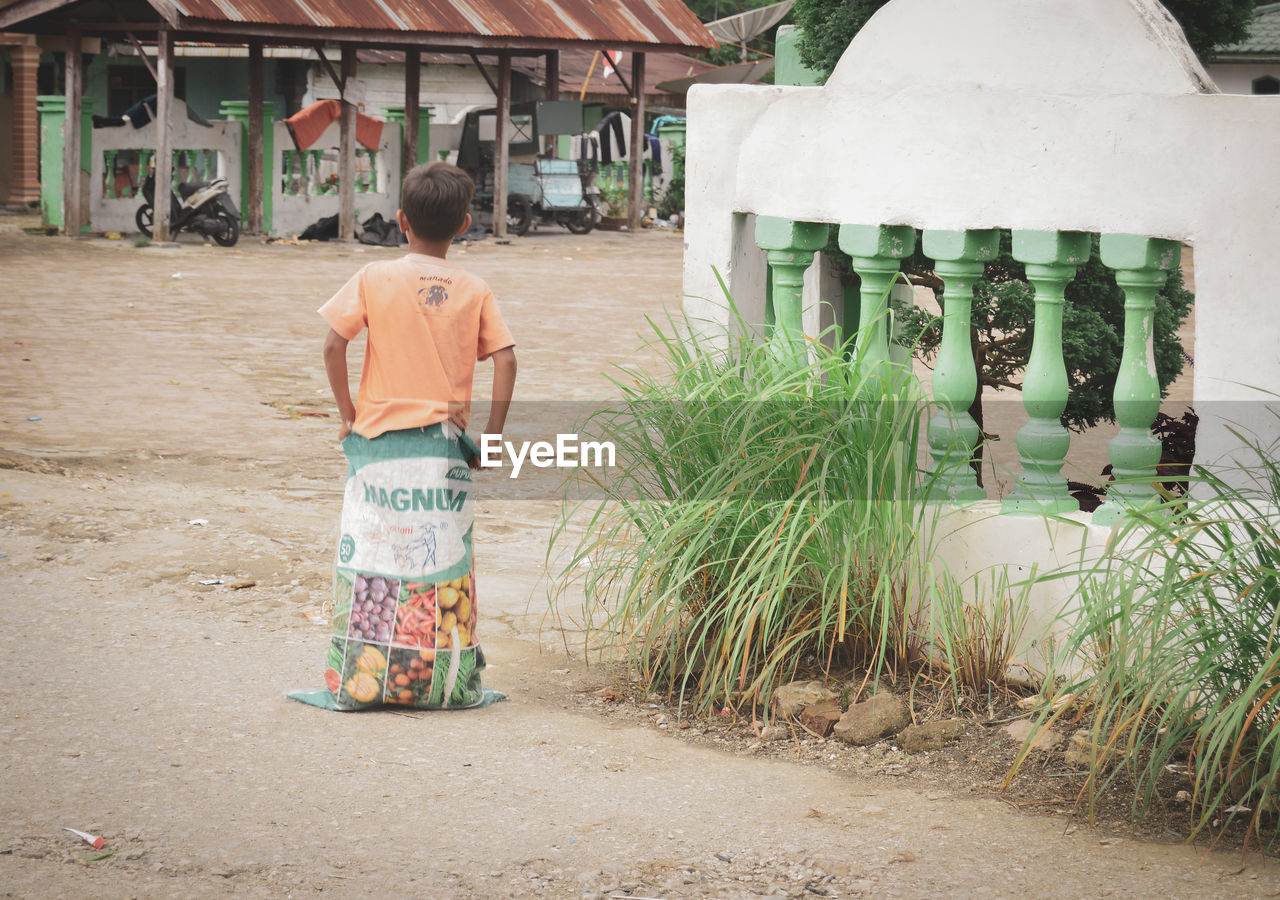 REAR VIEW OF BOY WALKING IN TRADITIONAL CLOTHING