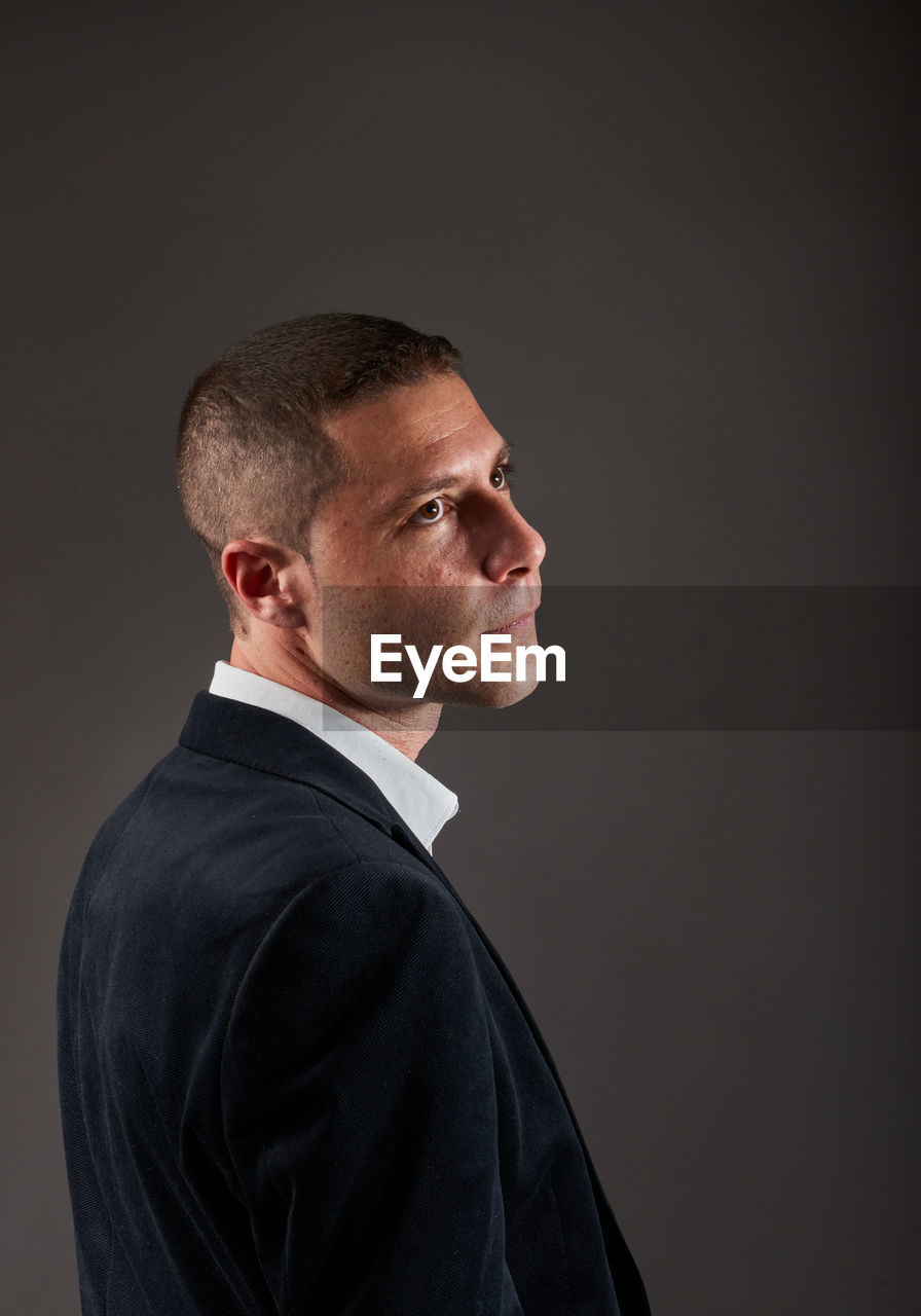 one person, studio shot, adult, men, portrait, indoors, business, formal wear, person, serious, looking, copy space, clothing, side view, businessman, headshot, profile view, mature adult, contemplation, gray, looking away, gray background, shaved head, black, emotion, business finance and industry, black background, waist up