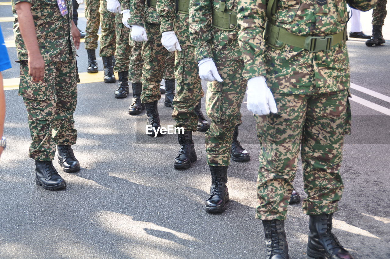 Low section of army soldiers wearing uniform standing on street in city