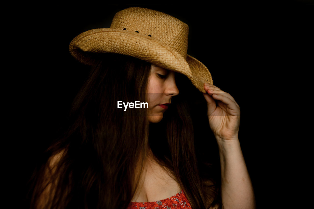 Sad lady in cowboy hat tipping her hat down in dramatic light