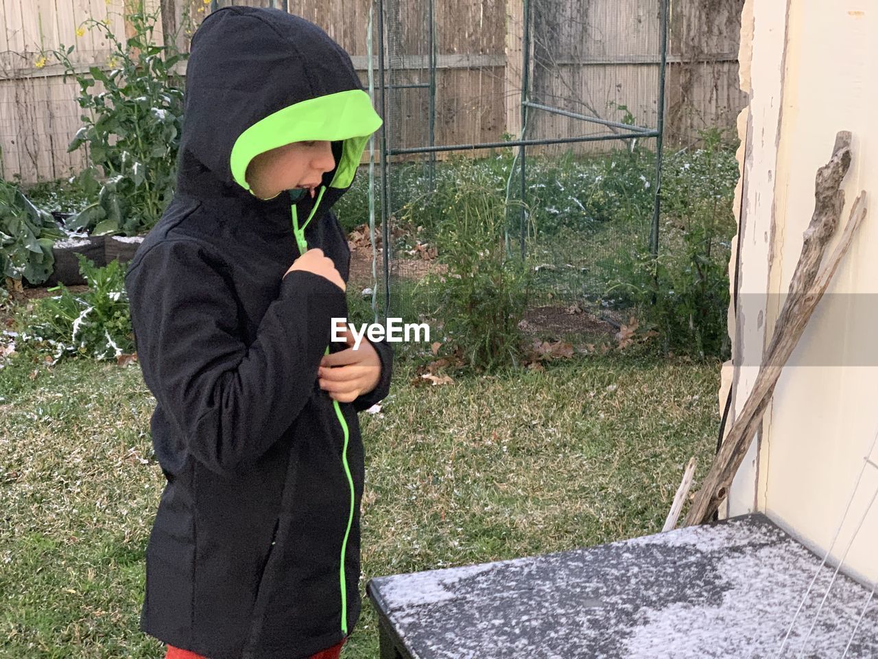 SIDE VIEW OF BOY HOLDING UMBRELLA STANDING OUTDOORS