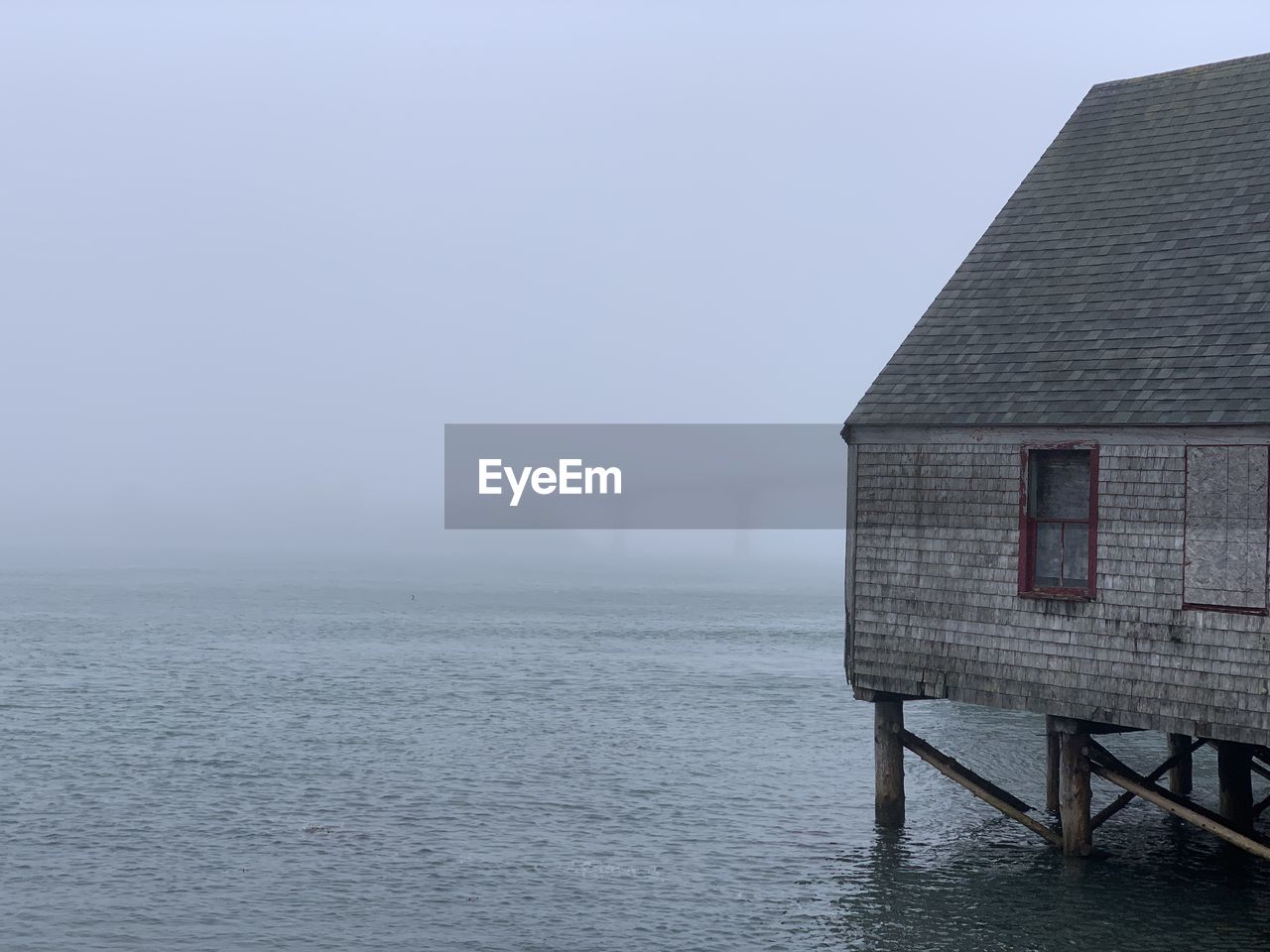 A fish smoking shack against the fog where you can barely see the bridge behind