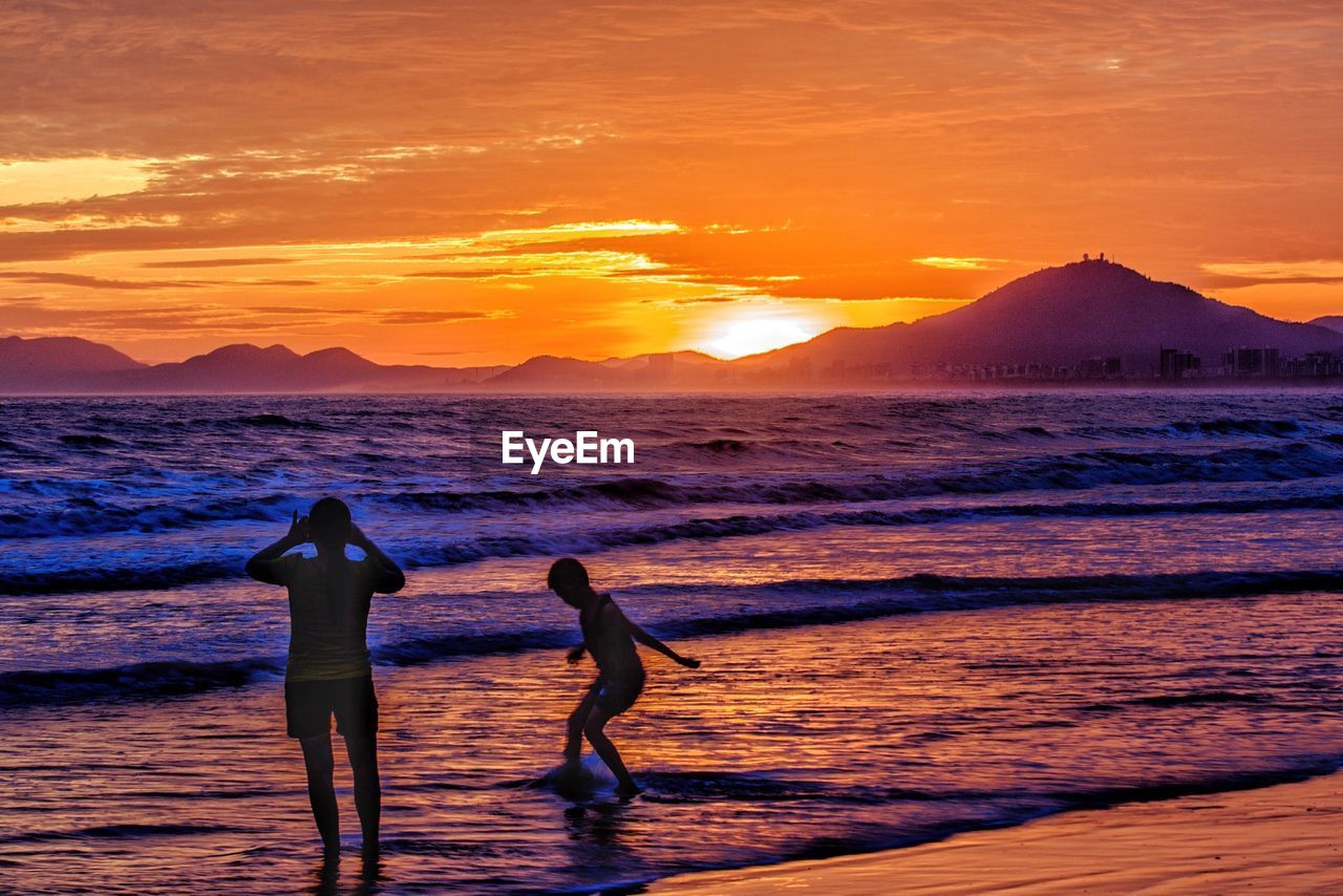 Man with his son enjoying sunset on beach