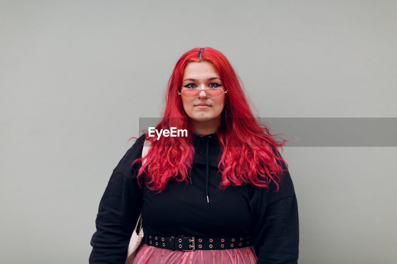 Portrait of beautiful young woman standing against wall