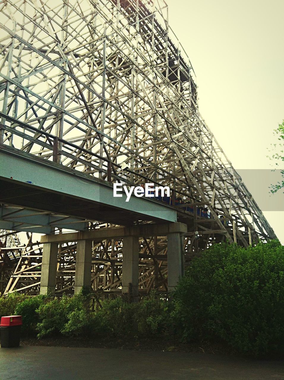 Low angle view of rollercoaster on metal bridge