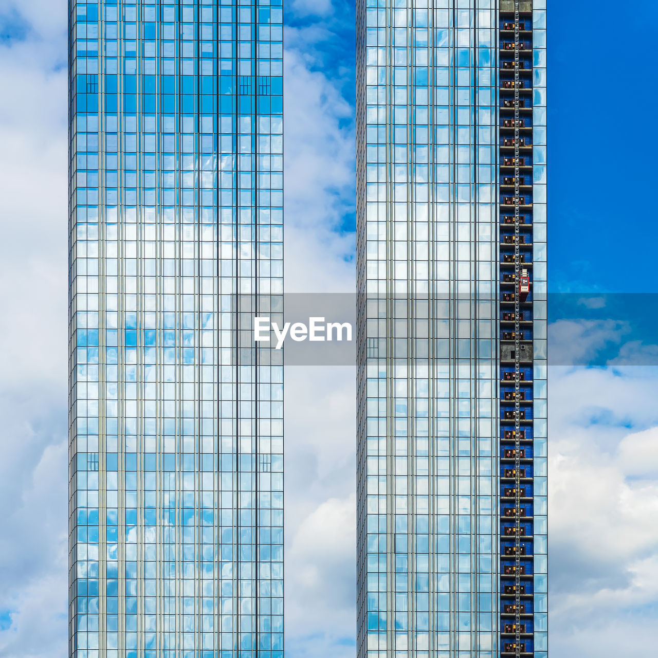 LOW ANGLE VIEW OF MODERN GLASS BUILDING AGAINST SKY