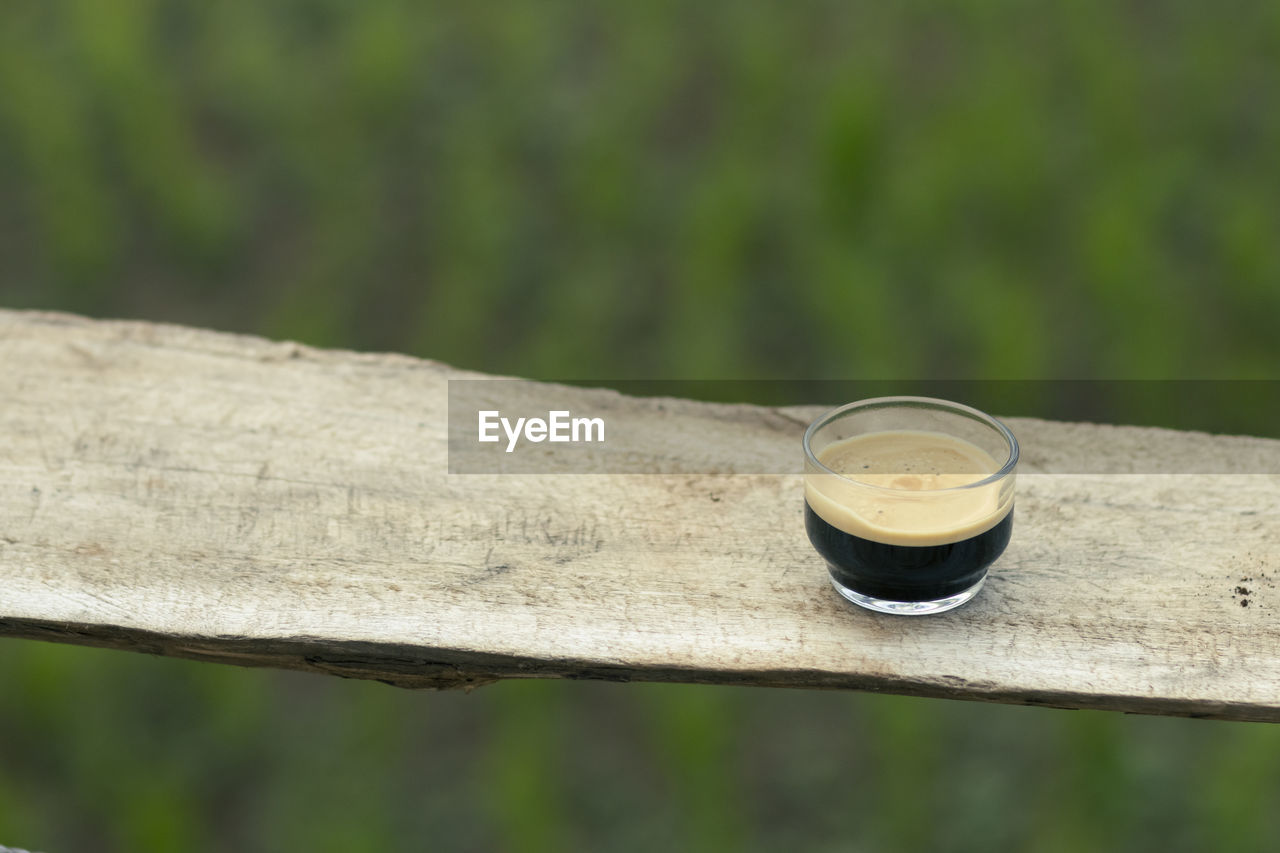 Selective focus black coffee americano in a clear glass placed on a wooden balcony high angle 