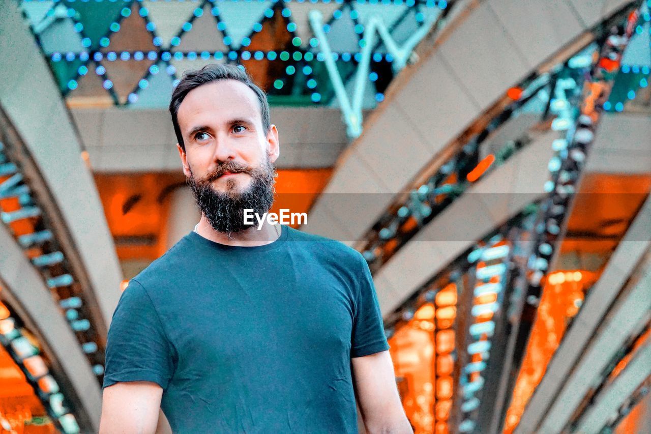 Low angle view of thoughtful man standing against building