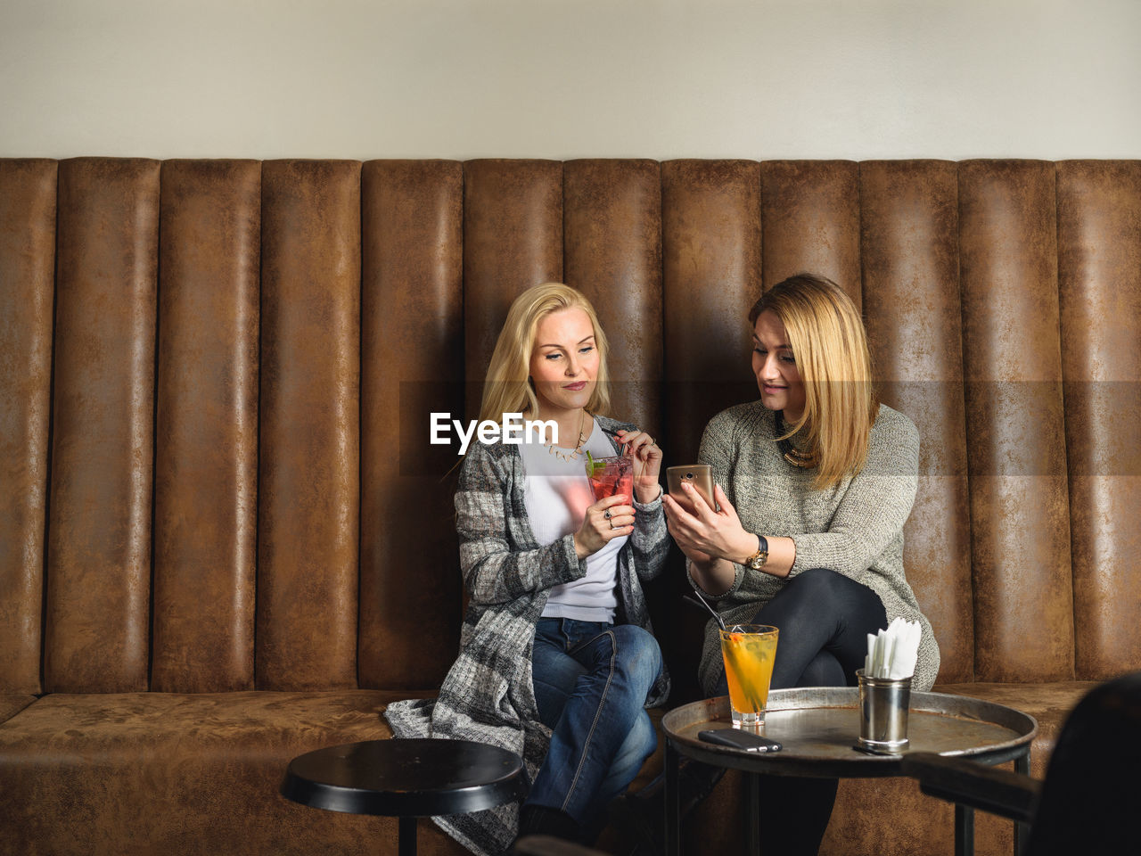 Female friends using smartphone in bar