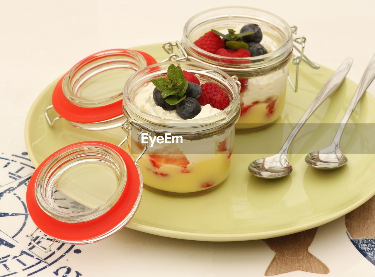 Fruits and yogurts in jars on table