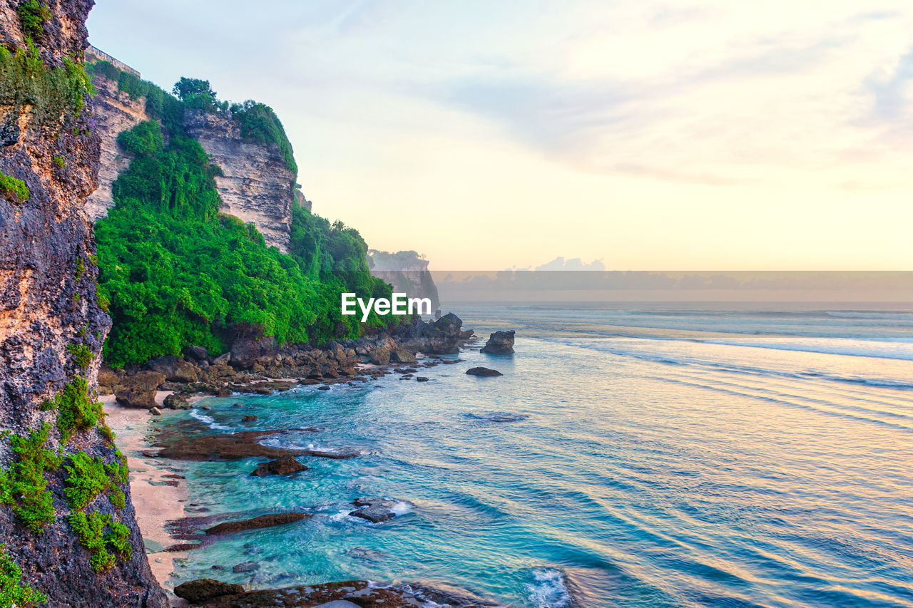 Beach at the foot of the cliff. scenic view of a secluded rocky beach before sunset.