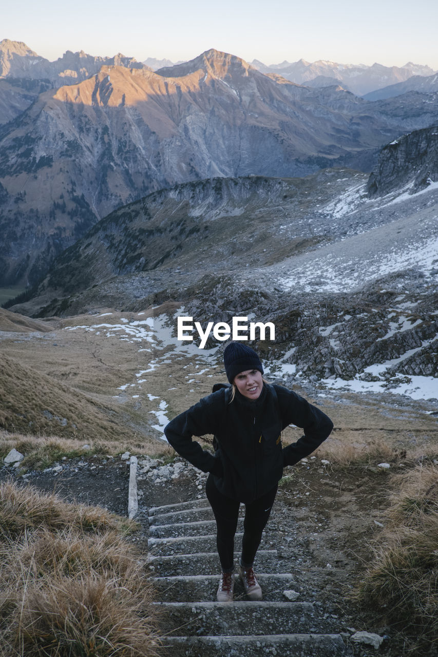 Full length of woman standing on steps against mountain range