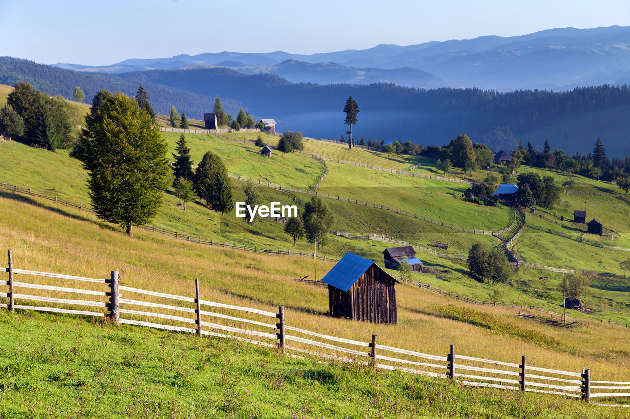 Trees and houses on field against mountains