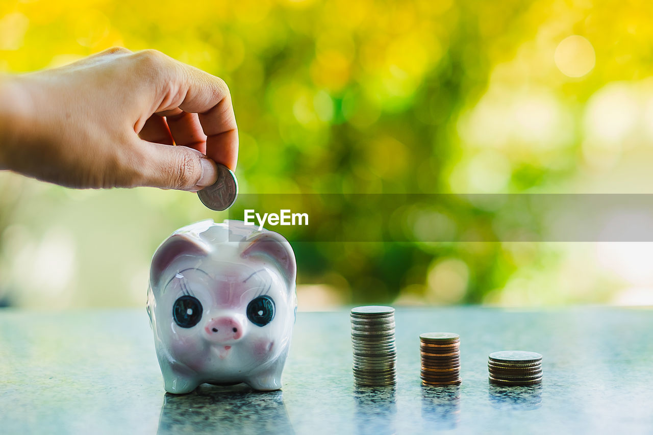 Close-up of hand inserting coin in piggy bank