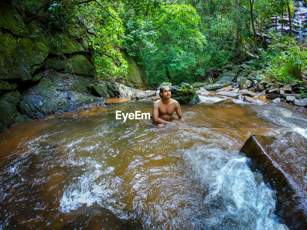 Man bathing in natural waterfall in forests at morning from different angle