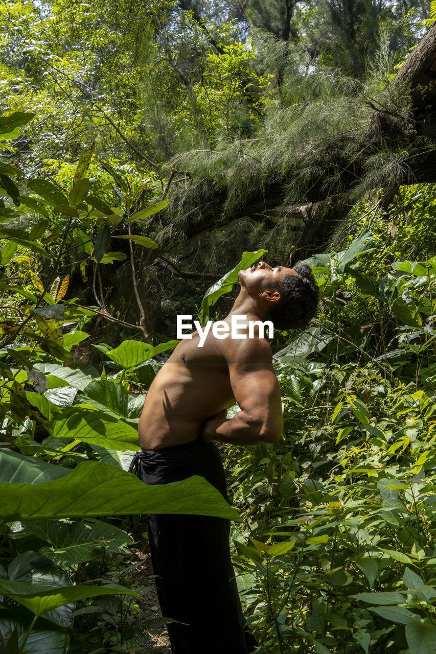 Man seen up close, without shirt doing stretches on yoga mat, exercise, latin america