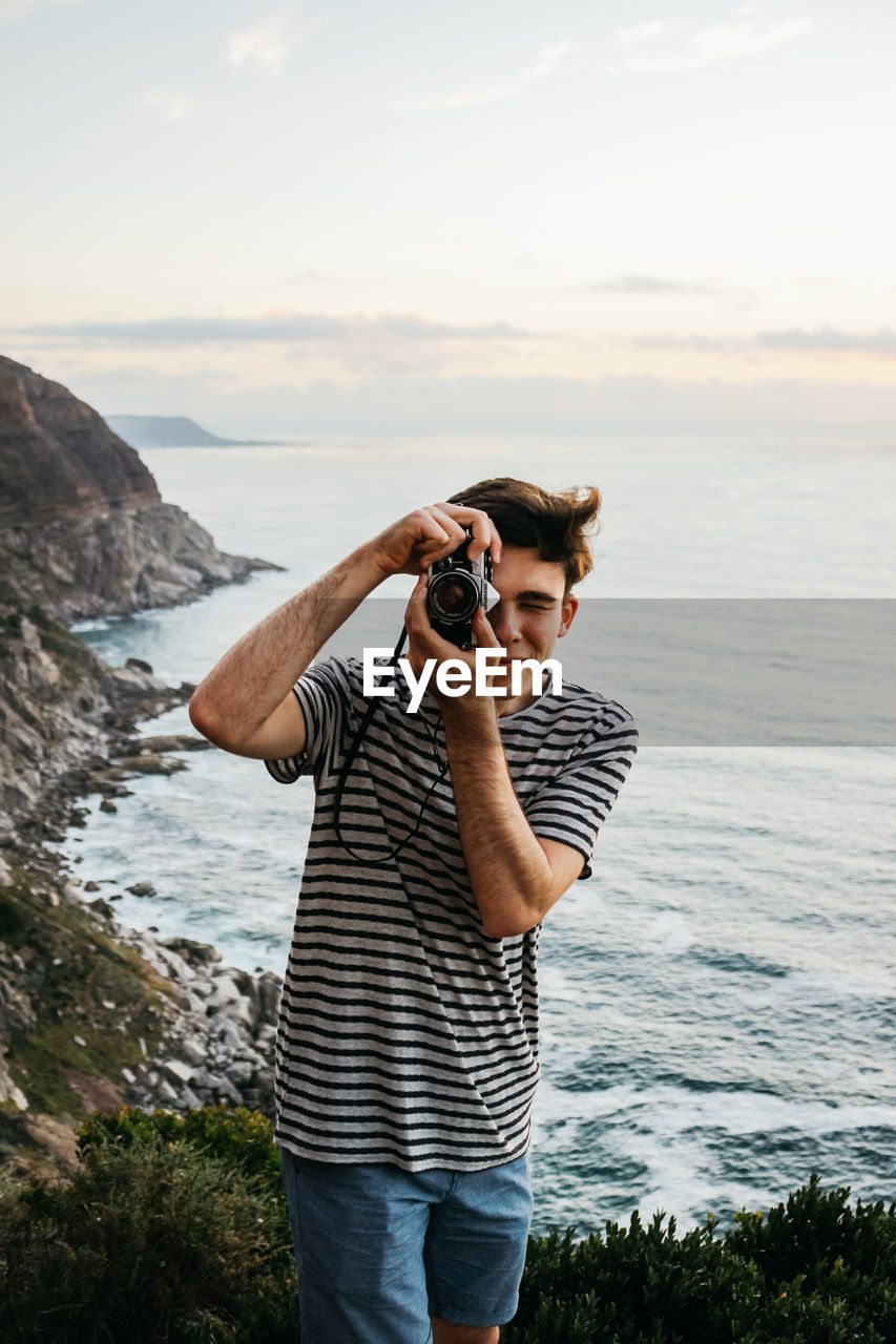 FULL LENGTH OF MAN PHOTOGRAPHING ON SEA