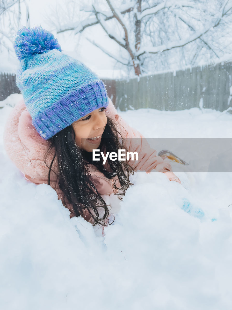 Diverse mixed race pre school toddler girl outdoors in winter playing with snow 