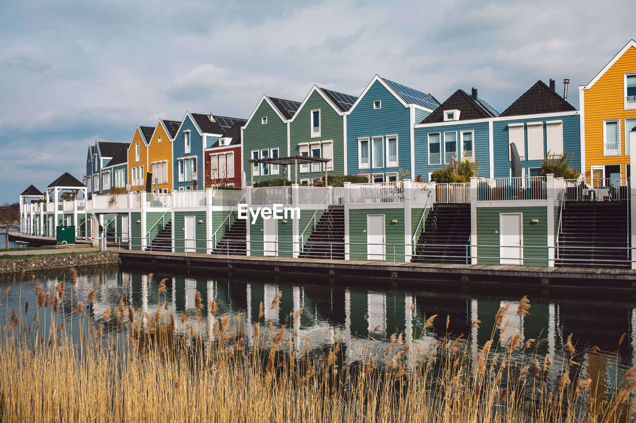 ROW OF HOUSES BY RIVER AGAINST SKY