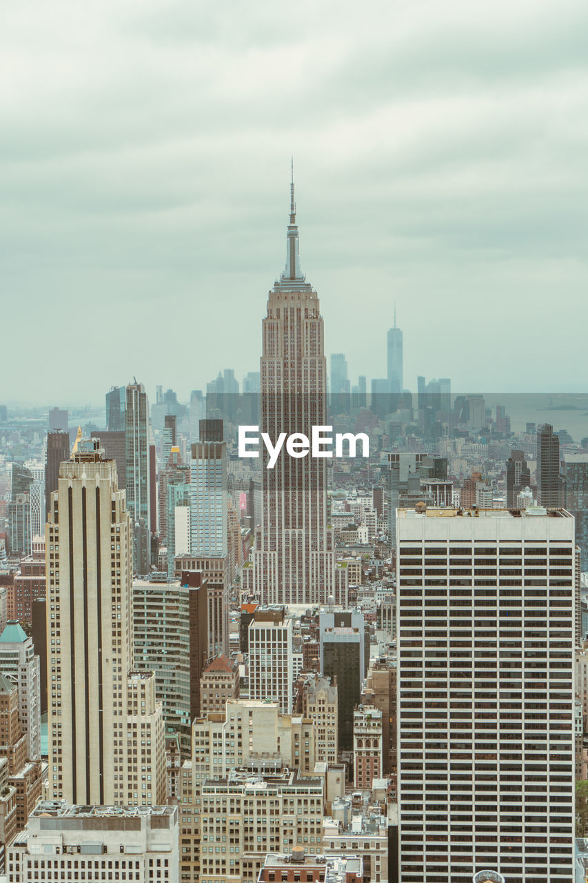 Empire state building from far against sky and buildings in background