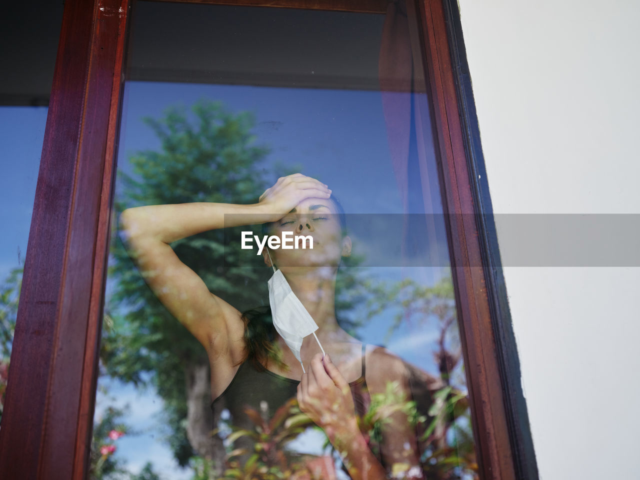 LOW ANGLE PORTRAIT OF YOUNG WOMAN AGAINST SKY SEEN THROUGH WINDOW
