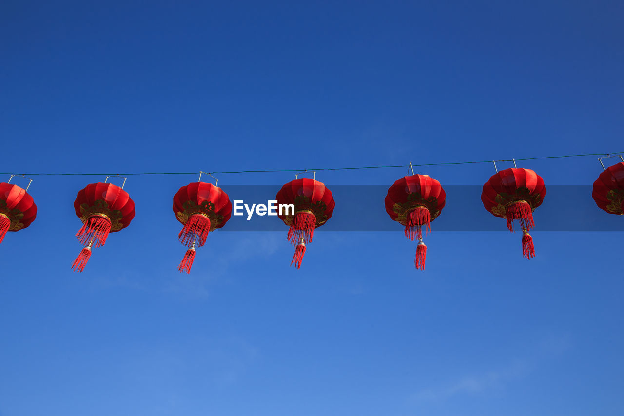 Low angle view of lanterns hanging against blue sky