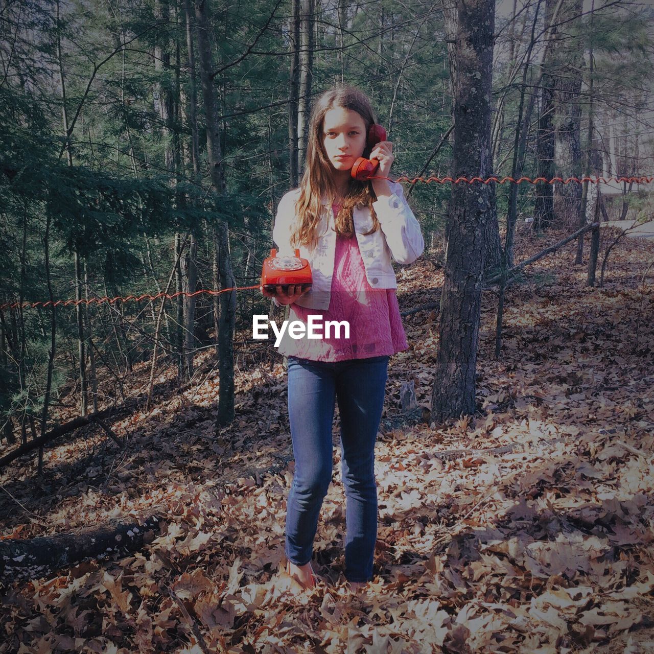 Teenage girl using landline phone in forest