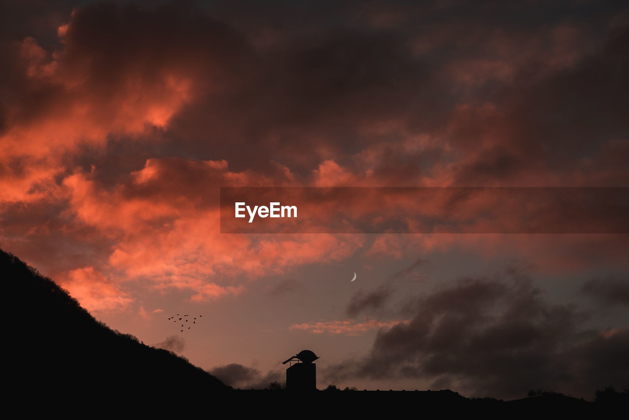 Low angle view of silhouette building against dramatic sky